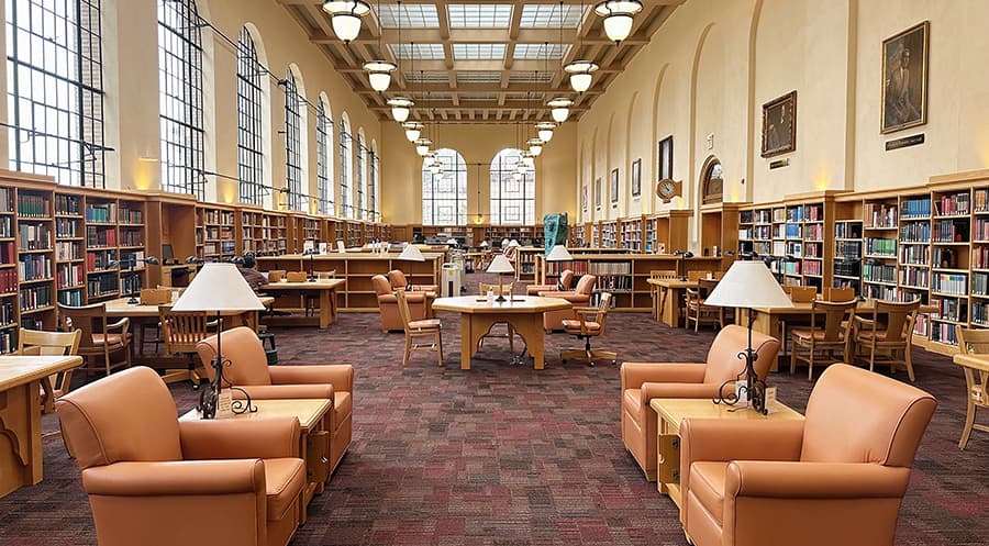 Large study room filled with book shelves, desks, and chairs.