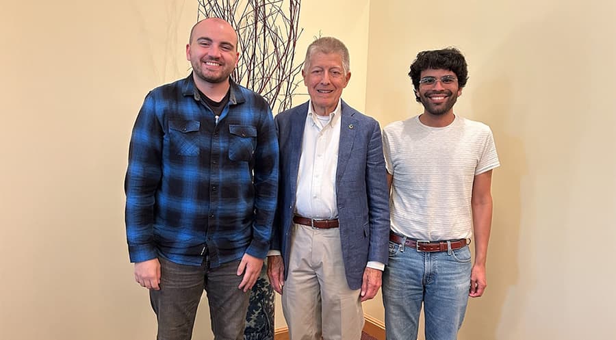 Three men posing for the camera in a meeting room.